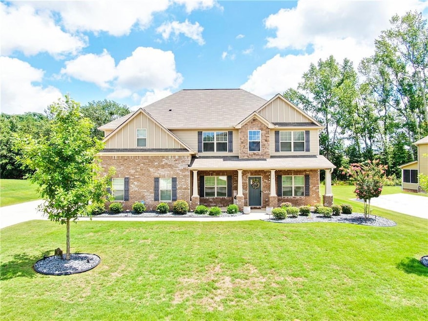 Craftsman-style home with board and batten siding, a porch, a front lawn, brick siding, and roof with shingles