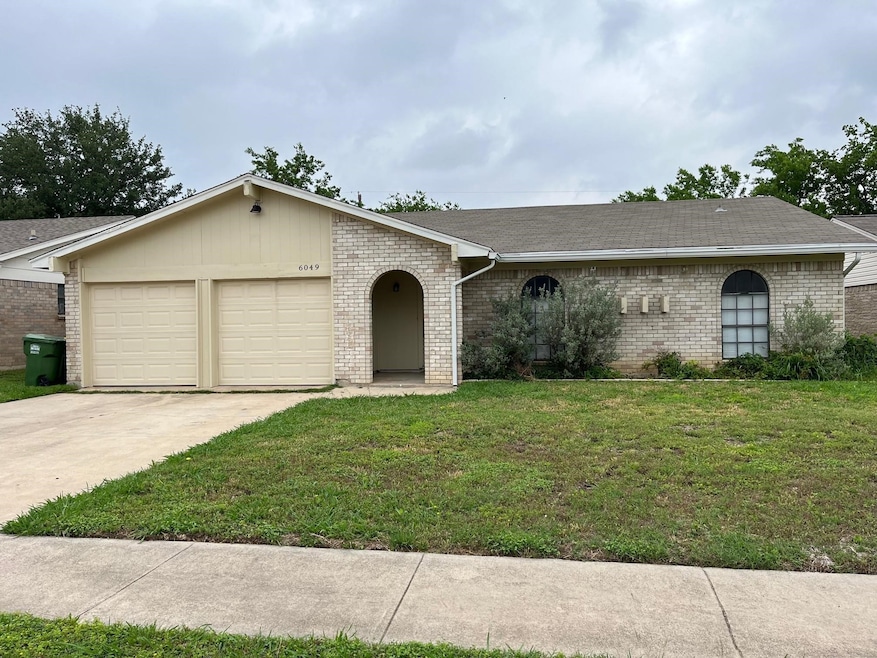 Single story home featuring a front lawn, driveway, roof with shingles, brick siding, and an attached garage