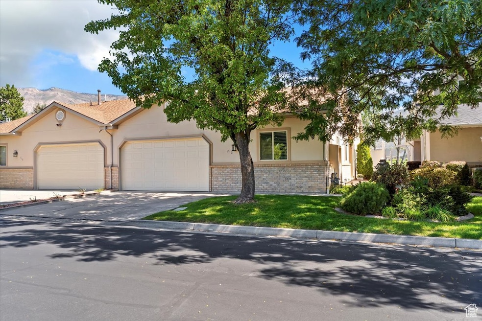 View of front of home featuring brick siding, concrete driveway, a garage, and stucco siding