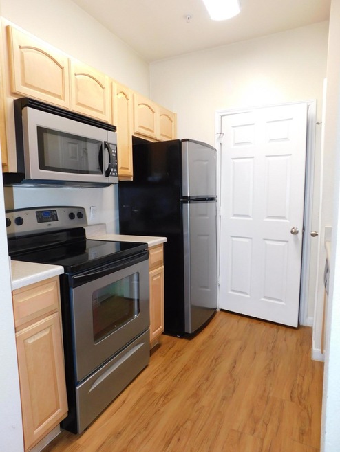 Kitchen with white range oven, stainless steel microwave, light wood-style floors, and light brown cabinets