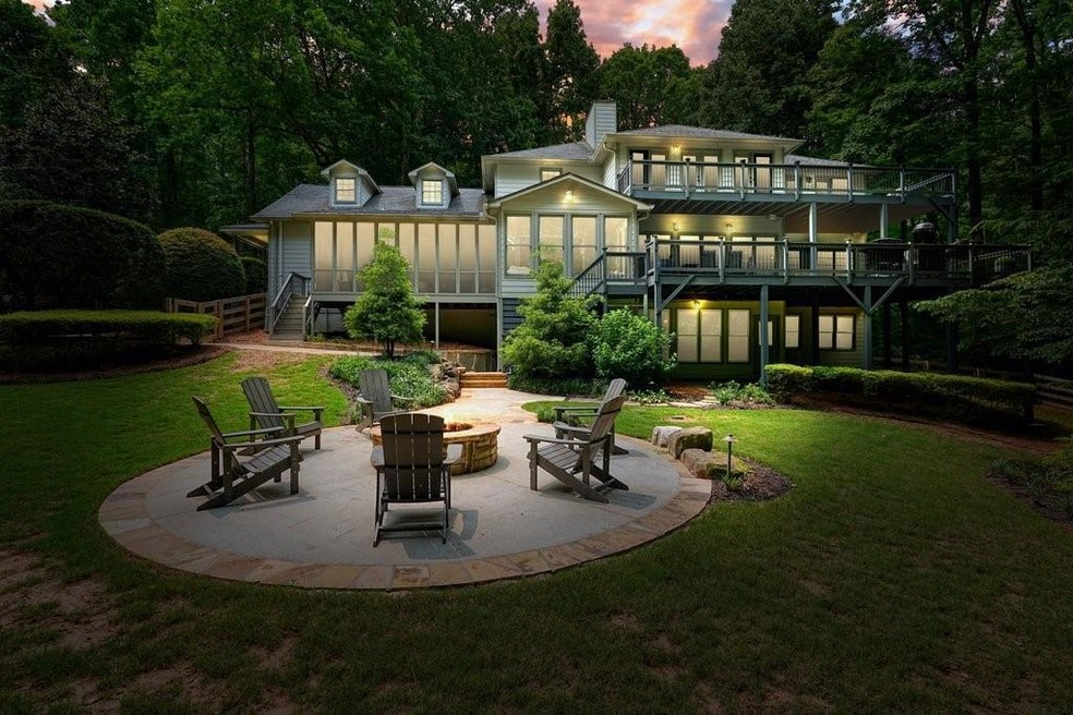 Back of property at dusk featuring a fire pit, stairway, a balcony, a lawn, and a patio area