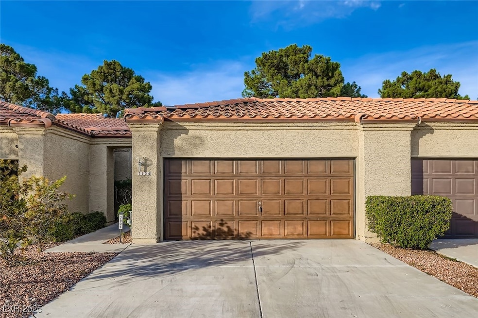 View of front of house with a tiled roof, stucco siding, and driveway