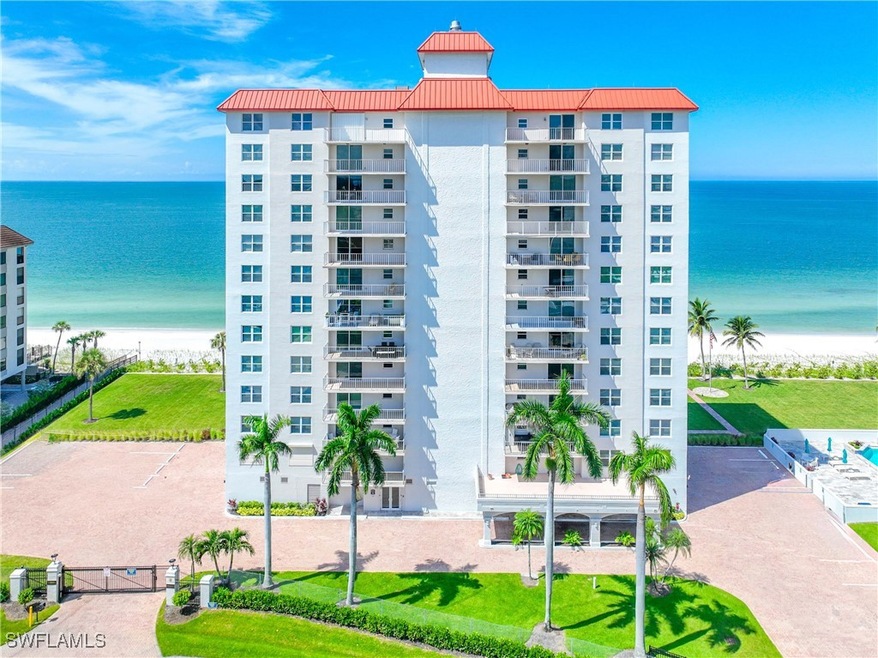 View of apartment building / complex featuring view of water and beach