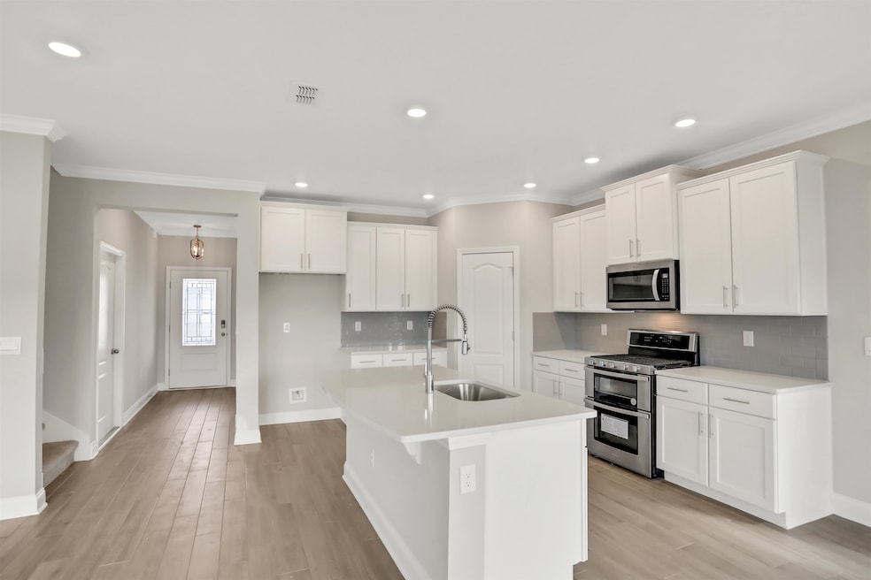 Kitchen with stainless steel appliances, white cabinets, tasteful backsplash, recessed lighting, and ornamental molding