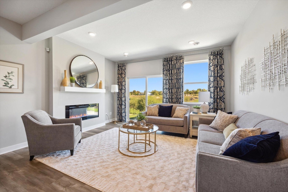 Living room off to the side with electric fireplace and backyard views. Photo of a previously built home, finishes, selections, colors, and layout may vary.