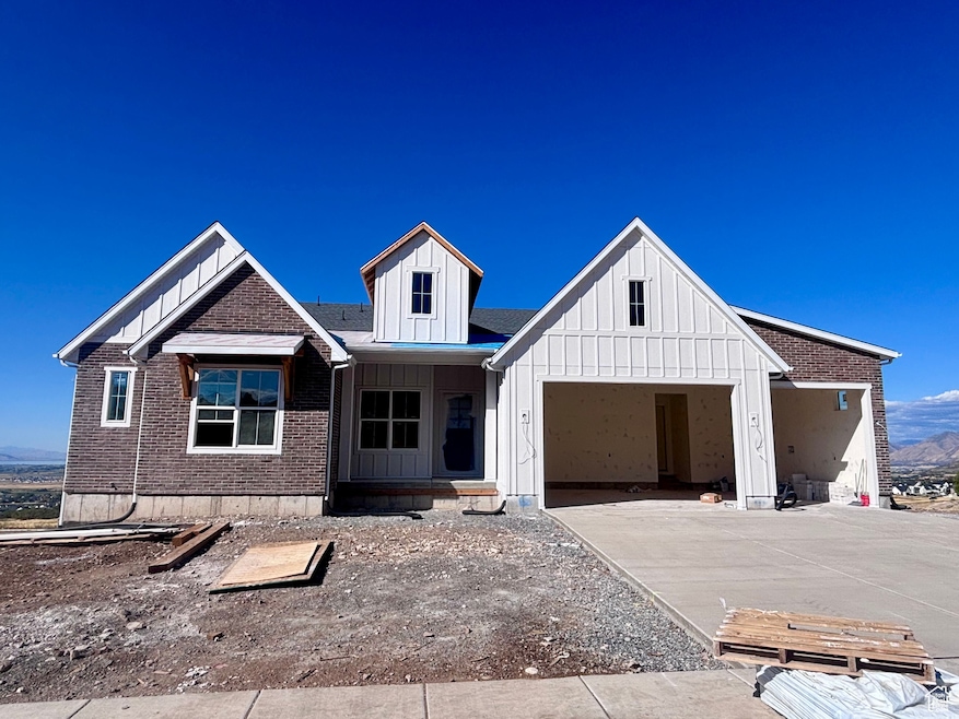 View of front of house with board and batten siding, covered porch, a garage, concrete driveway, and brick siding