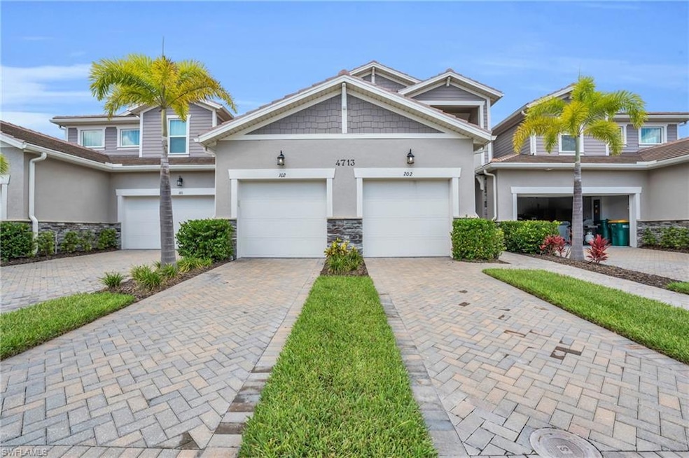 Multi unit property with stucco siding, stone siding, decorative driveway, and a garage
