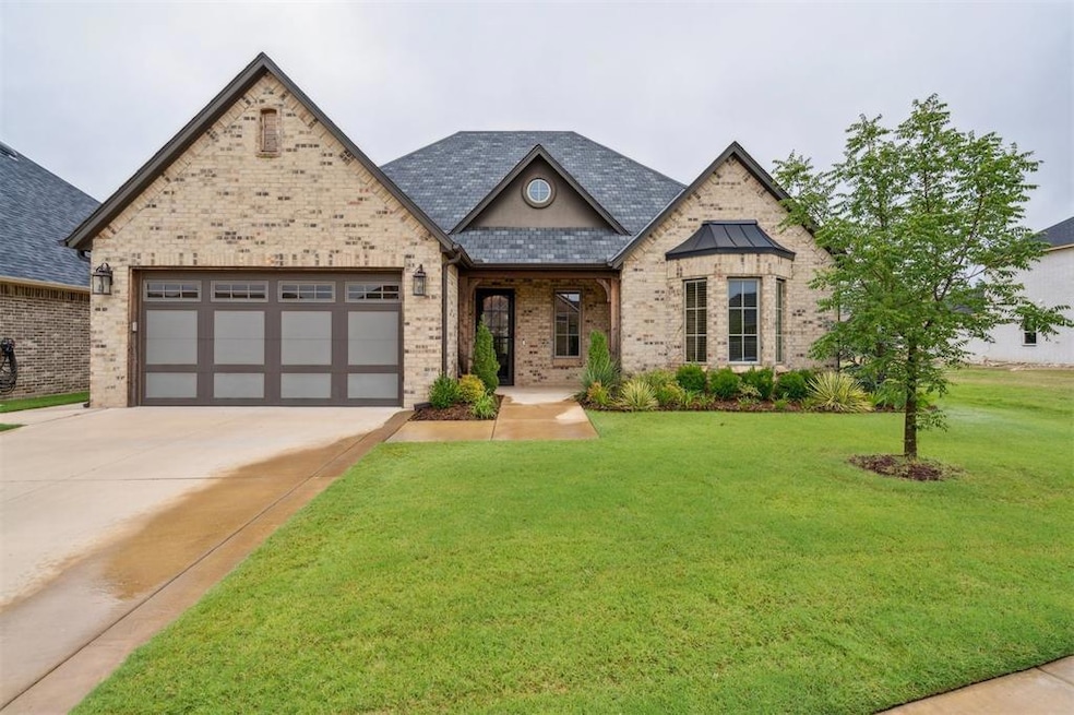View of front of home featuring brick siding, a porch, a front lawn, driveway, and a garage