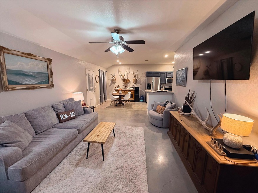 Living area featuring a ceiling fan, recessed lighting, and finished concrete flooring