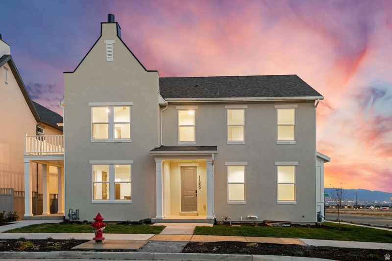 Traditional-style home with stucco siding, roof with shingles, and a balcony