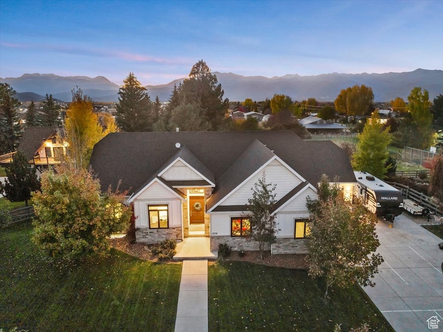 View of front facade featuring stone siding, a front yard, and a mountain view