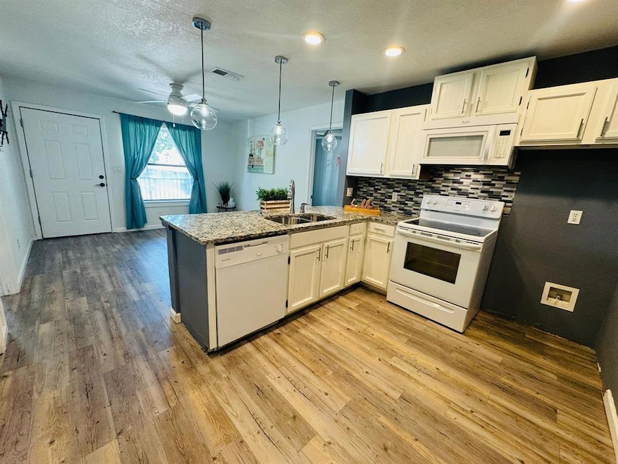 Kitchen featuring white appliances, a peninsula, 