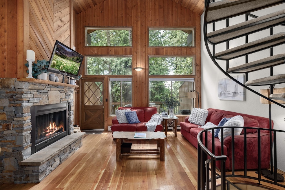 Living room with high vaulted ceiling, wood-type flooring, a fireplace, wood walls, and wood ceiling