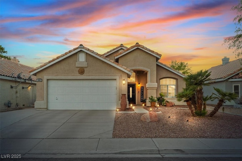 Mediterranean / spanish-style house featuring concrete driveway, a tile roof, stucco siding, a garage, and a chimney