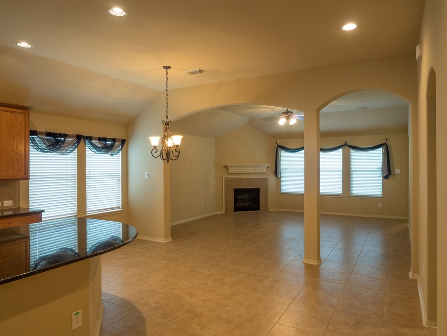 It's what's inside that makes this house special.  High ceilings, tile floors, a gas fireplace, architectural arches, and an open floor plan are just waiting for you in this gently used home.  This view is from the right of the kitchen looking through to the back windows.