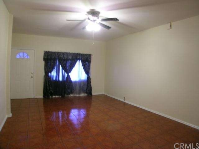 Large living room with tile flooring and a fan lam