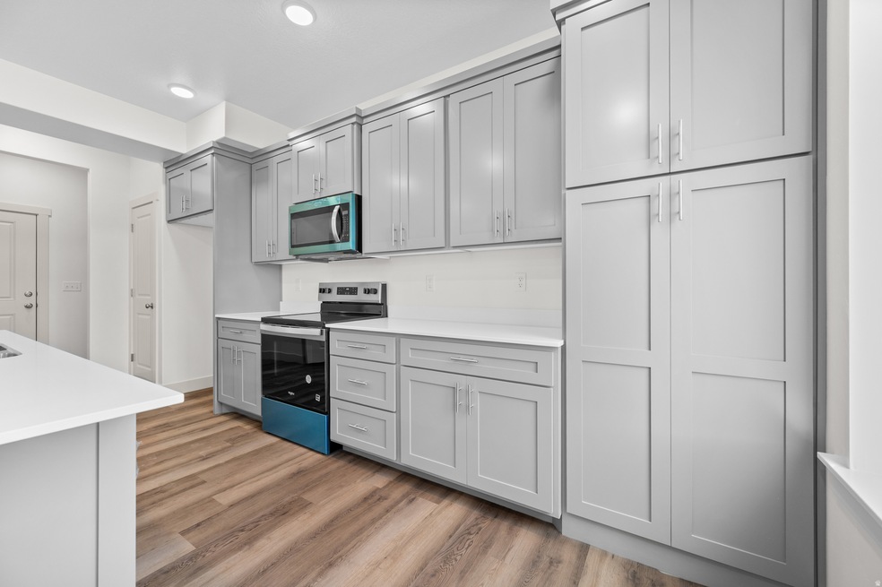 Kitchen featuring appliances with stainless steel finishes, light wood-style floors, gray cabinetry, light stone countertops, and recessed lighting
