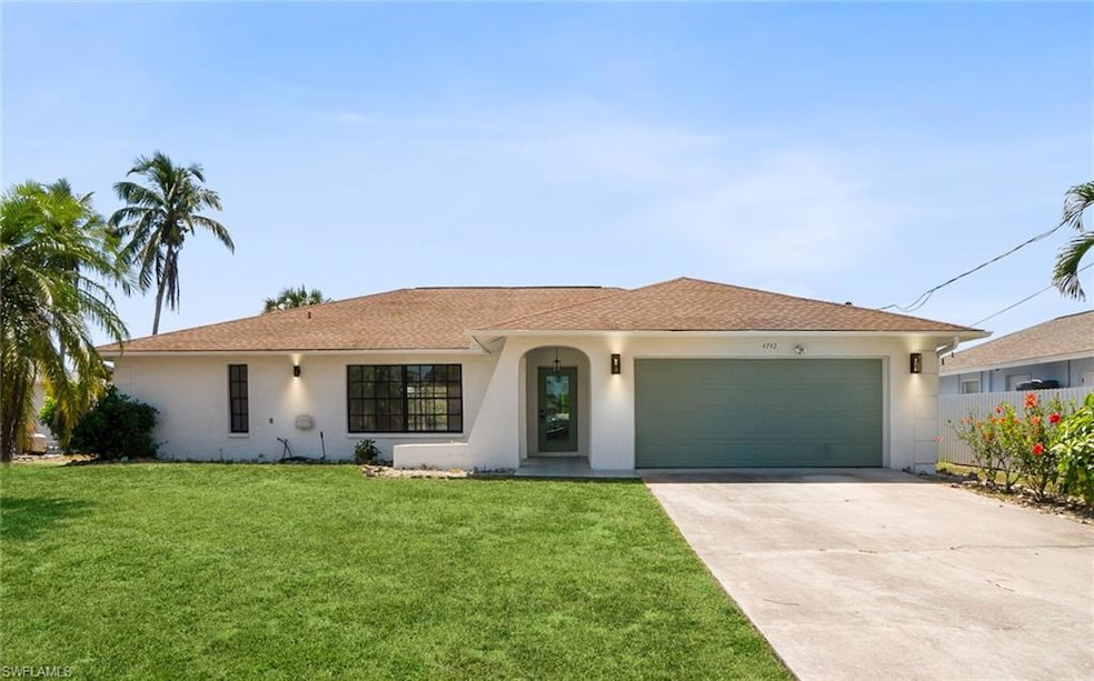 Ranch-style home with driveway, a front yard, fence, an attached garage, and stucco siding