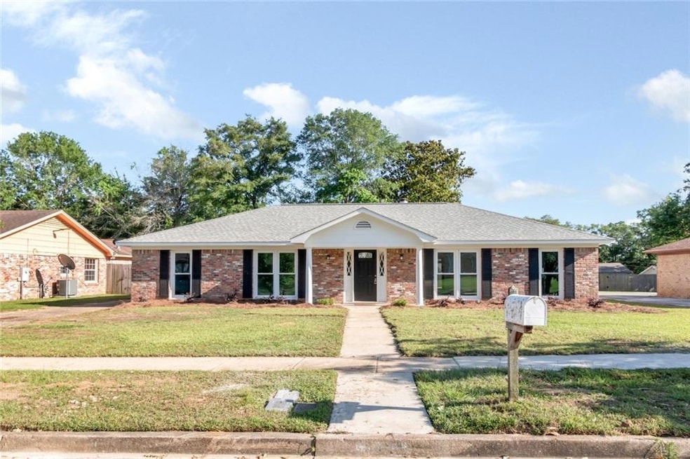View of front of property with a front lawn, a shingled roof, and brick siding