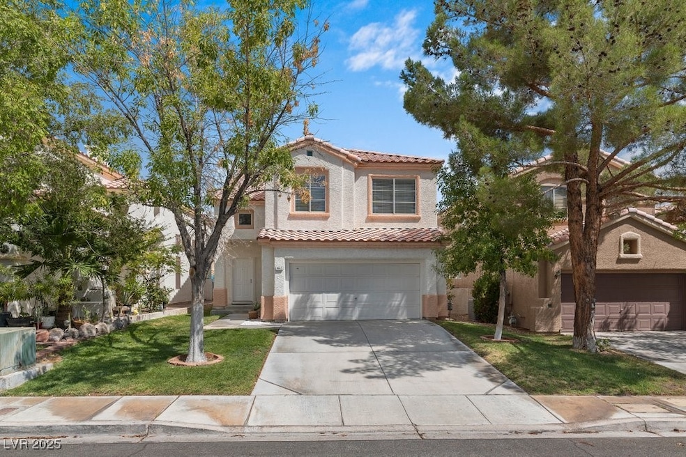Mediterranean / spanish-style house with a tile roof, a garage, concrete driveway, a front lawn, and stucco siding