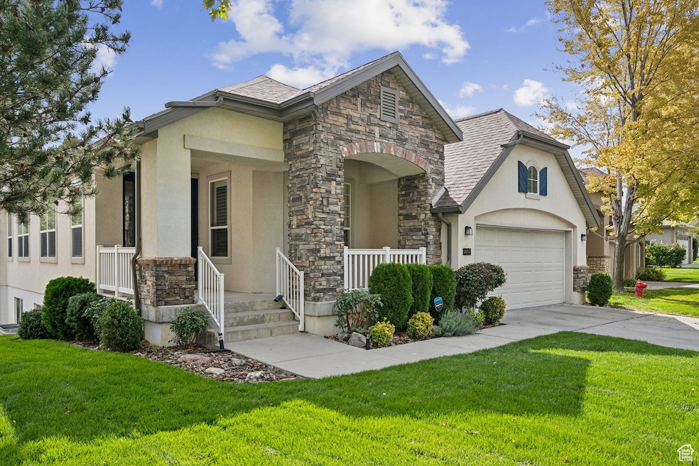 View of front of house featuring stone siding, stucco siding, covered porch, and a front lawn