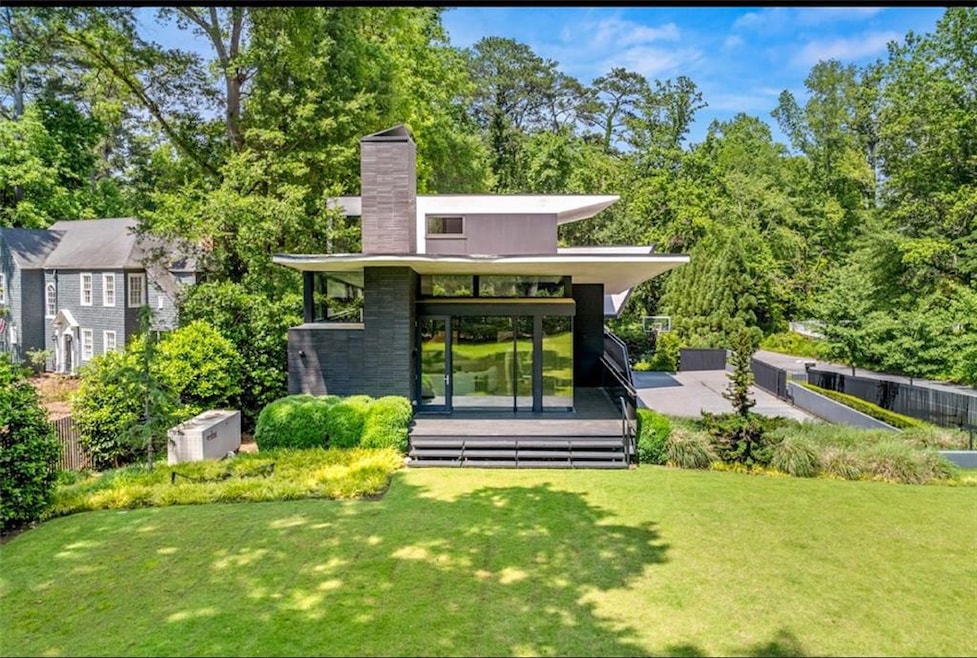Rear view of house with a chimney, a yard, and a deck