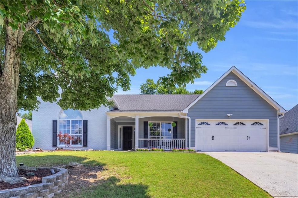 View of front of property featuring a porch, a garage, a front lawn, and driveway
