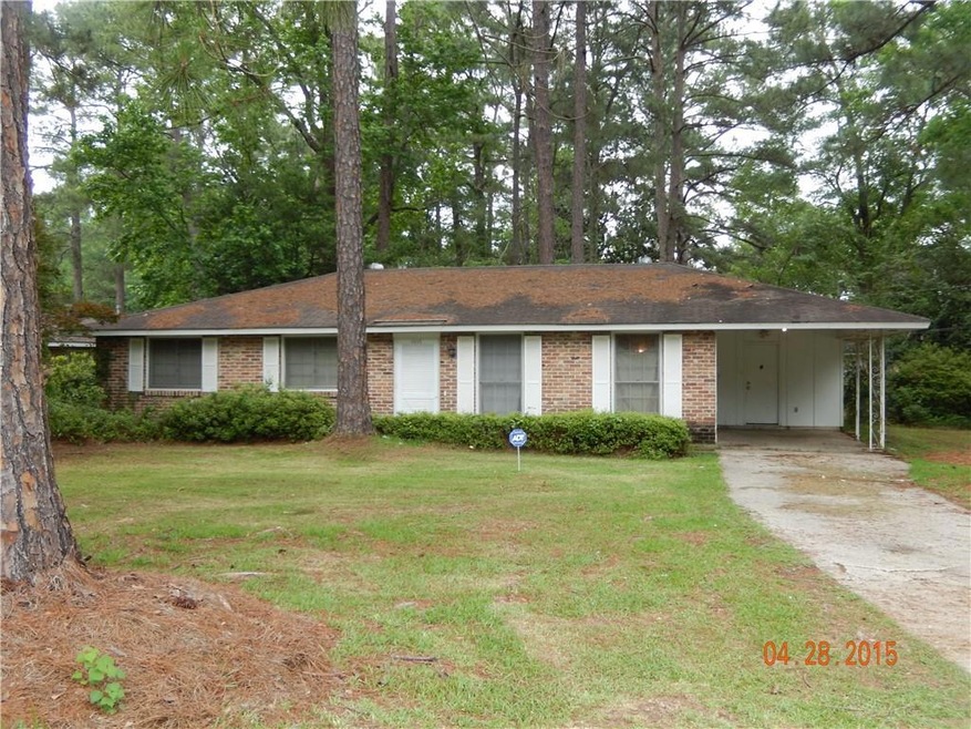 Single story home with a front lawn, driveway, brick siding, and an attached carport