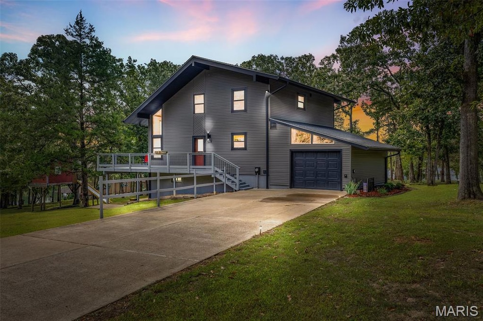 Contemporary home with driveway, a yard, an attached garage, a deck, and stairway