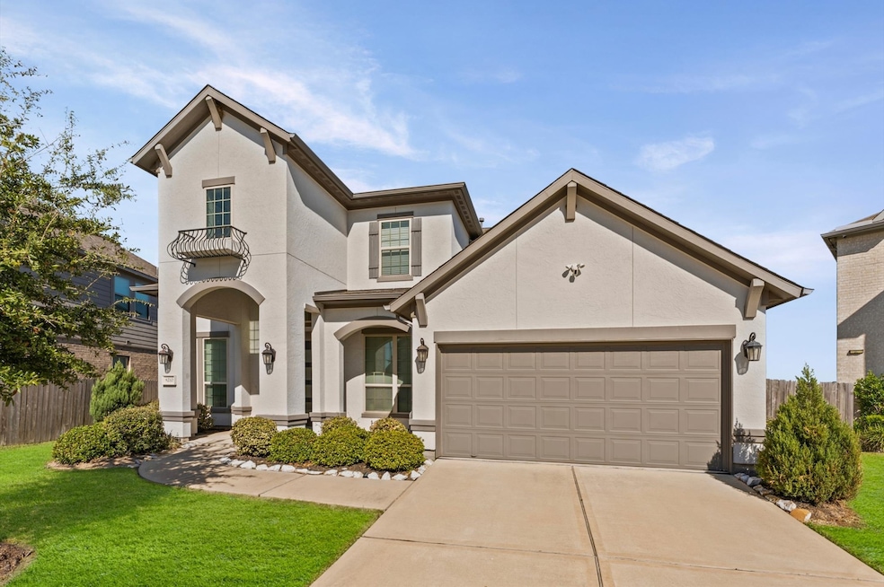 Charming two-story home features a modern exterior with a clean, light facade and well-maintained landscaping. It includes a two-car garage, arched entryway, and decorative balcony. The driveway and front lawn offer a welcoming approach.