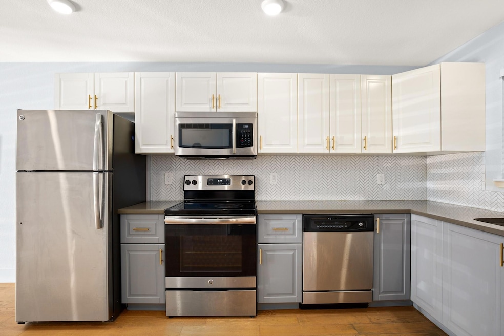 Kitchen with gray cabinets, white cabinets, appli