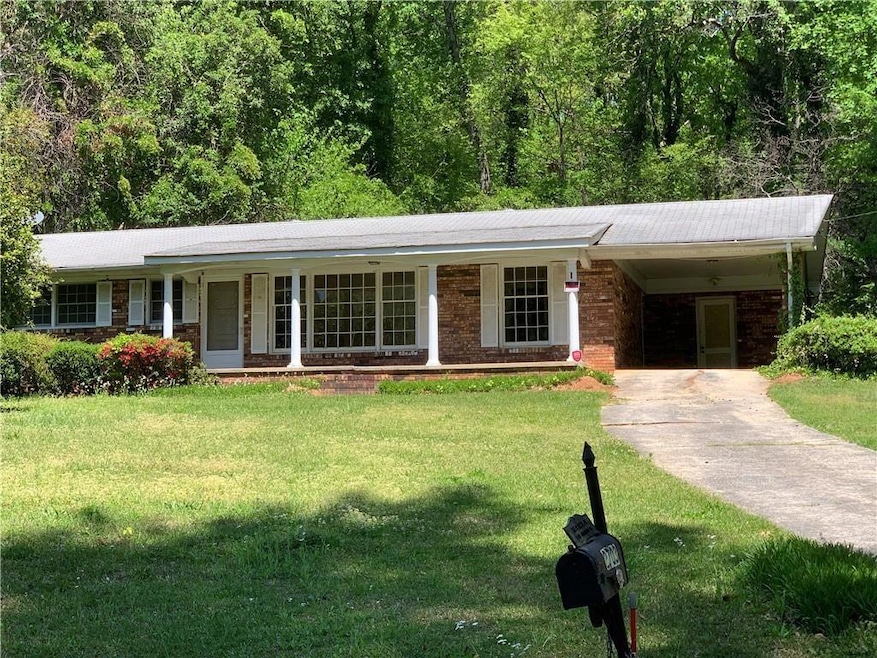 Single story home with a front yard, an attached carport, driveway, and covered porch