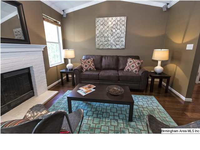 Living room with hardwood floors, painted brick fi