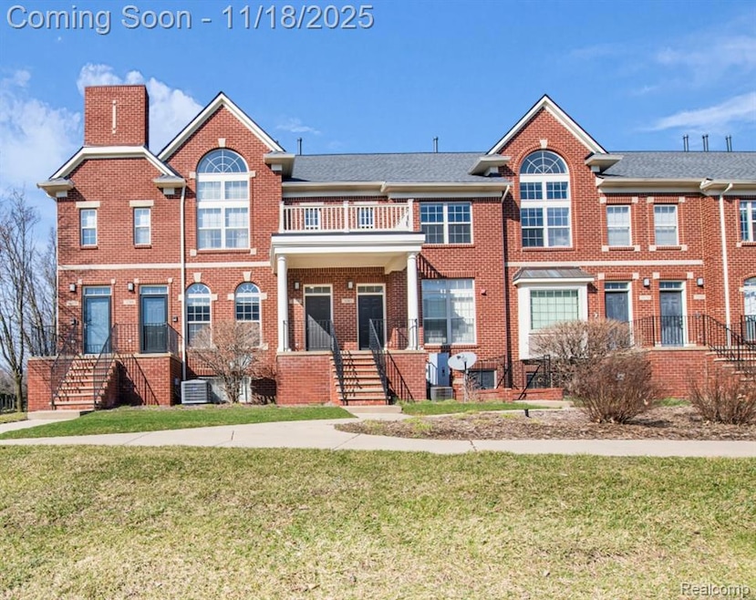 Colonial-style house featuring brick siding, a front lawn, and a balcony