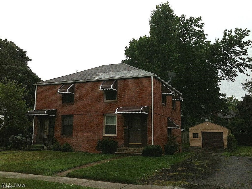 View of front of property with a front lawn, an outdoor structure, and a garage