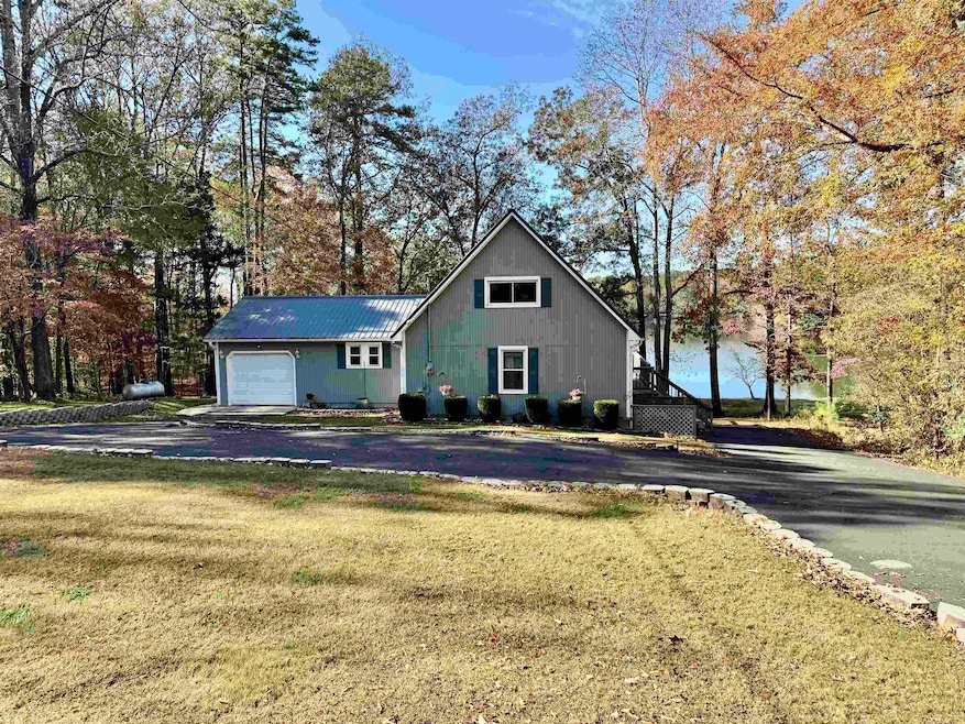 View of front of house with a metal roof, a front lawn, asphalt driveway, and an attached garage