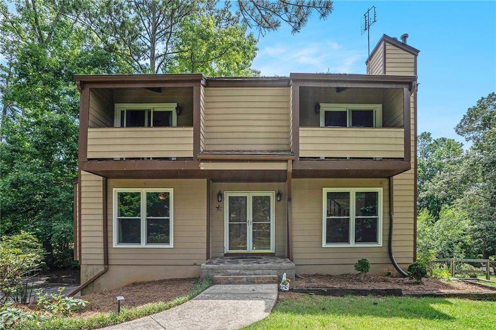 View of front of home featuring a chimney and a balcony