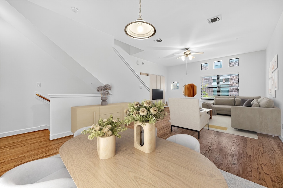 Bright, open living area with hardwood floors, modern furnishings, and neutral decor. Features a cozy seating area, dining space, and large windows for natural light. Perfect for comfortable living and entertaining.