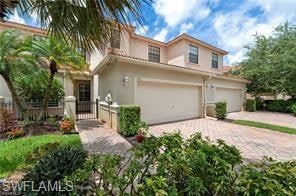 View of front of house featuring a gate, stucco siding, decorative driveway, and a garage