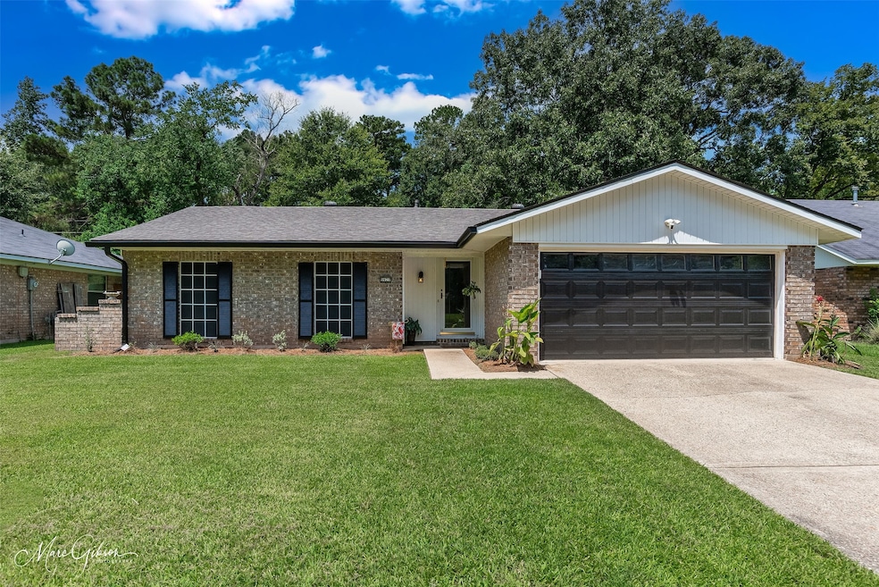 Ranch-style home featuring a front lawn, concrete driveway, brick siding, and a garage