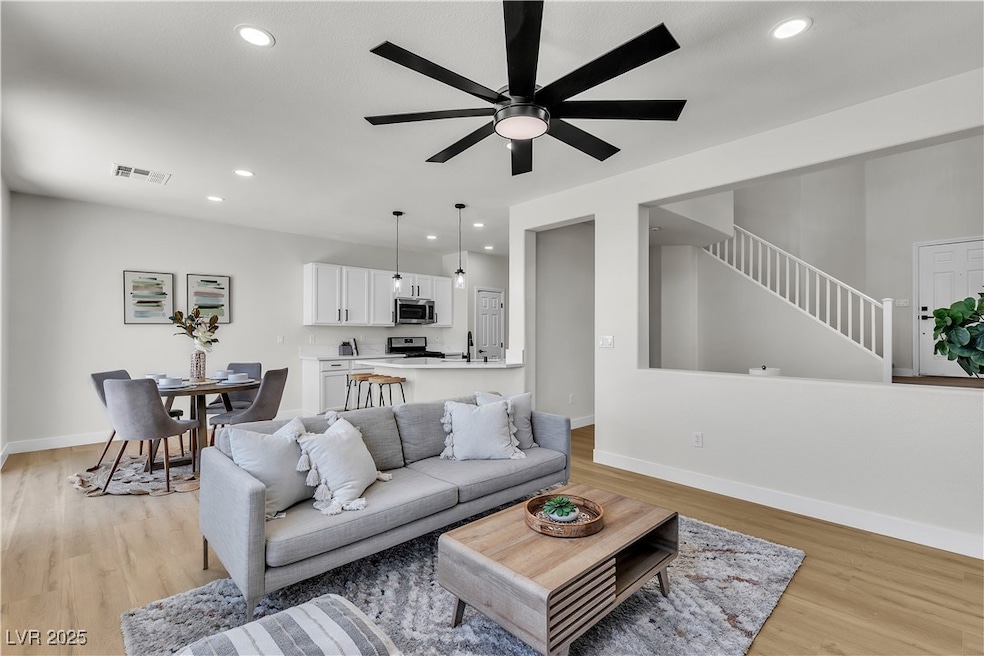 Living room featuring ceiling fan, light wood-type