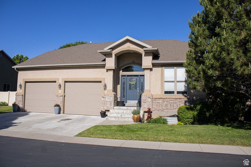 Ranch-style home with concrete driveway, a garage, stucco siding, a front lawn, and stone siding