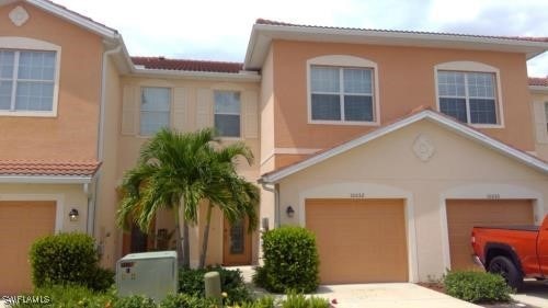 View of front facade with stucco siding, a garage,