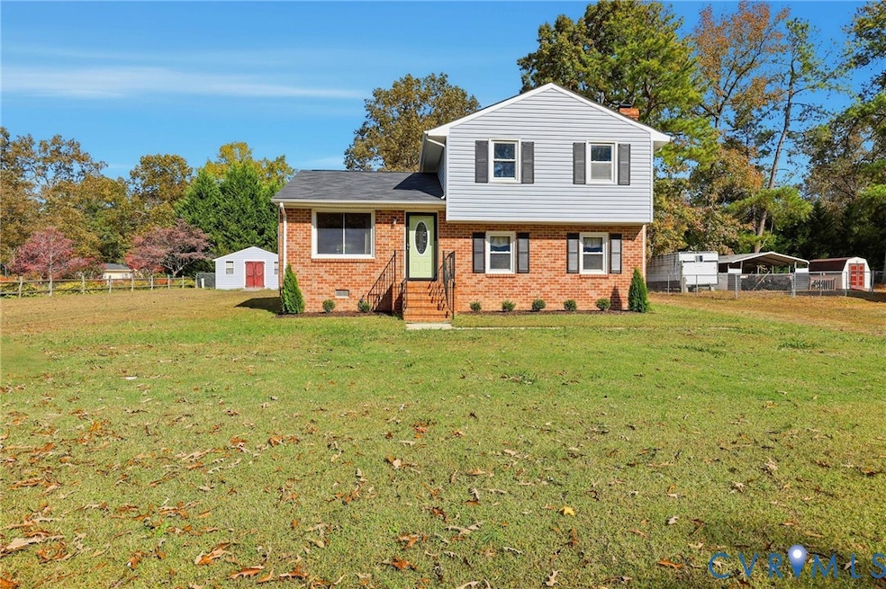 Split level home with brick siding, a detached carport, a storage unit, and crawl space