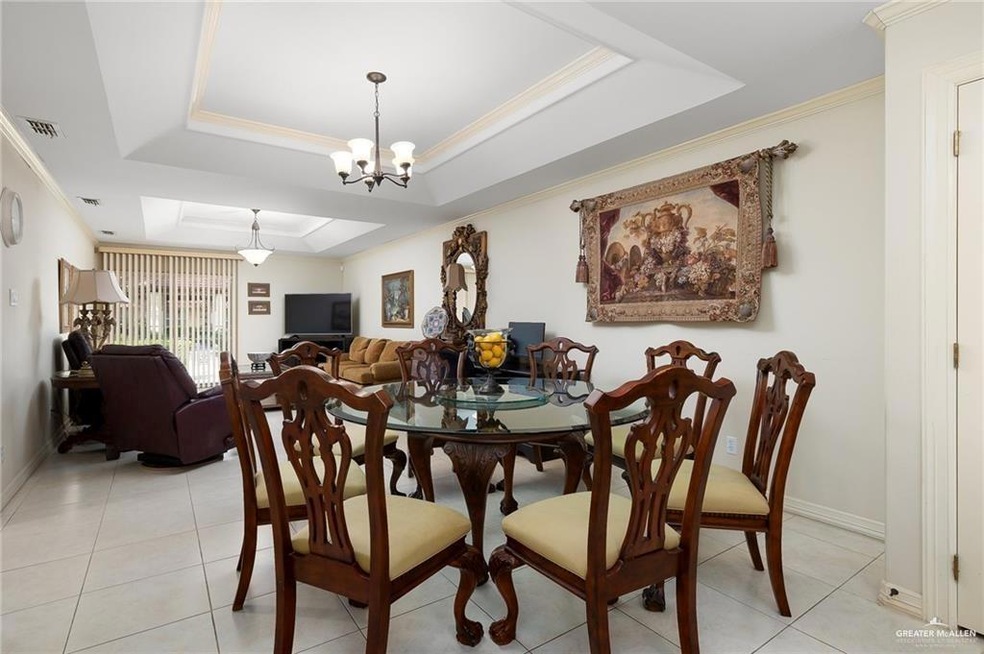 Dining space with a raised ceiling, a chandelier, light tile patterned flooring, and ornamental molding