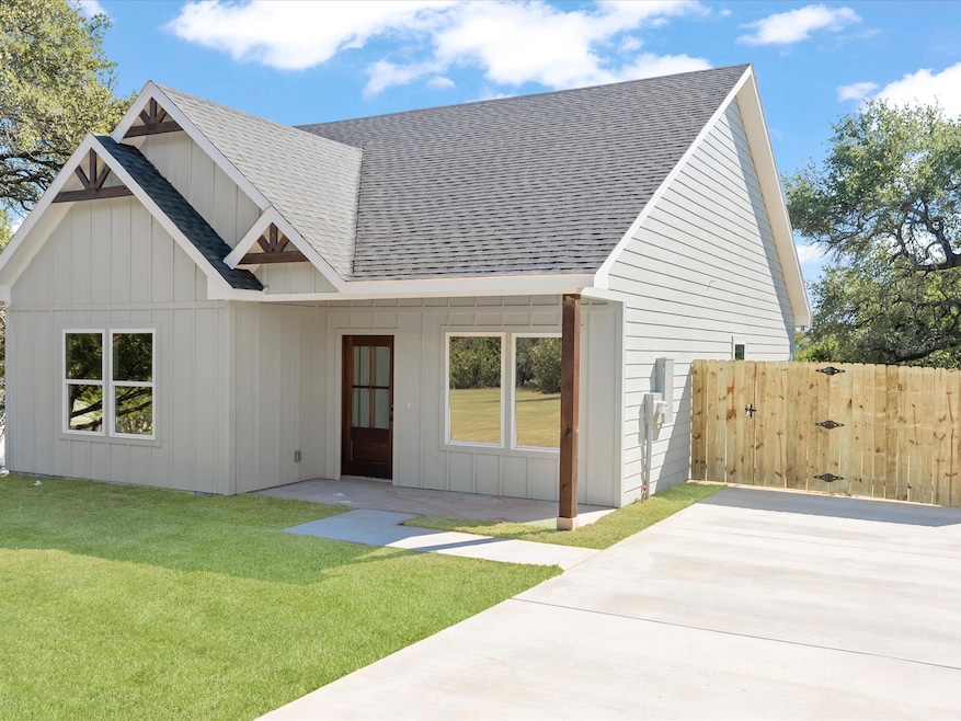 View of front facade with roof with shingles, board and batten siding, and a gate