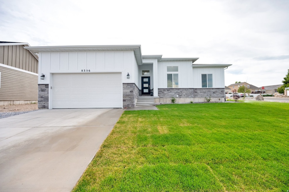 View of front of house featuring concrete driveway, a front yard, stone siding, board and batten siding, and an attached garage