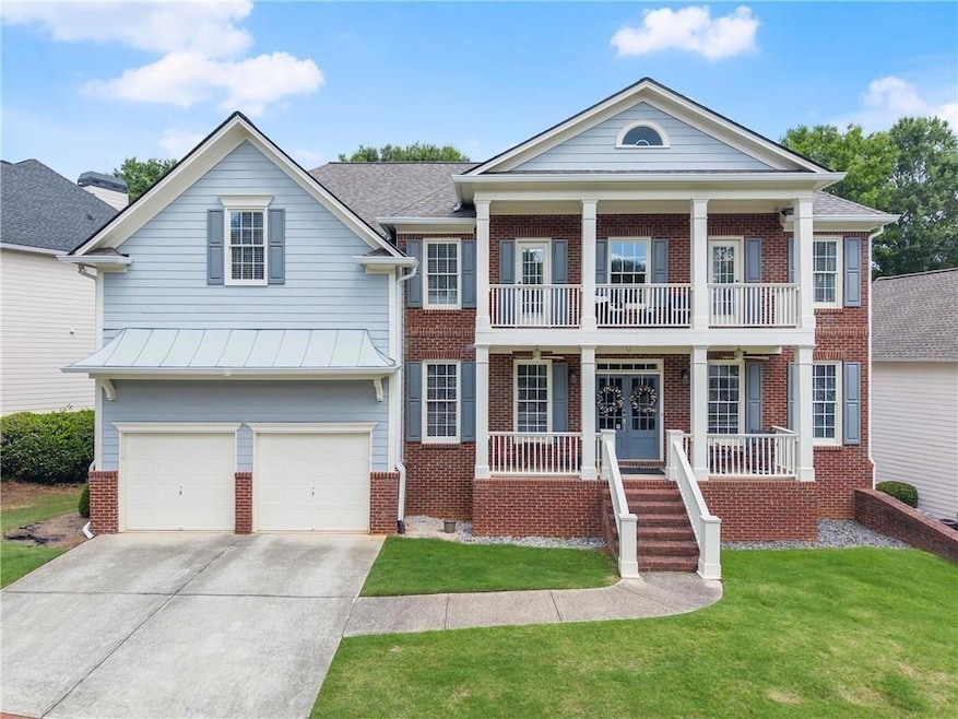 Neoclassical home featuring brick siding, covered porch, a balcony, and driveway