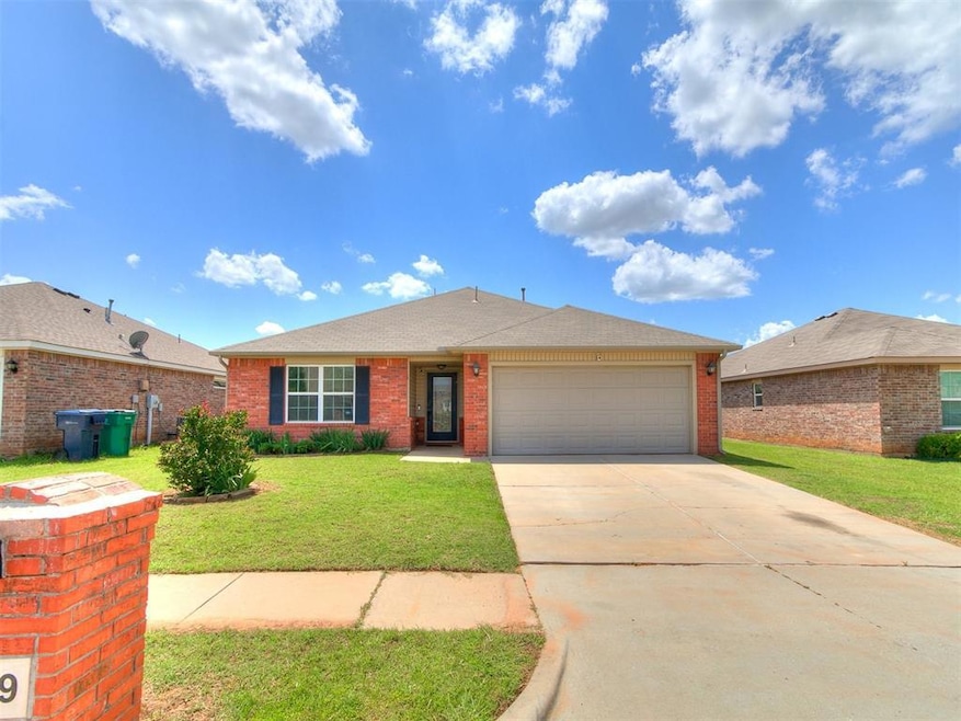 Single story home featuring a garage, brick siding, concrete driveway, and a front yard
