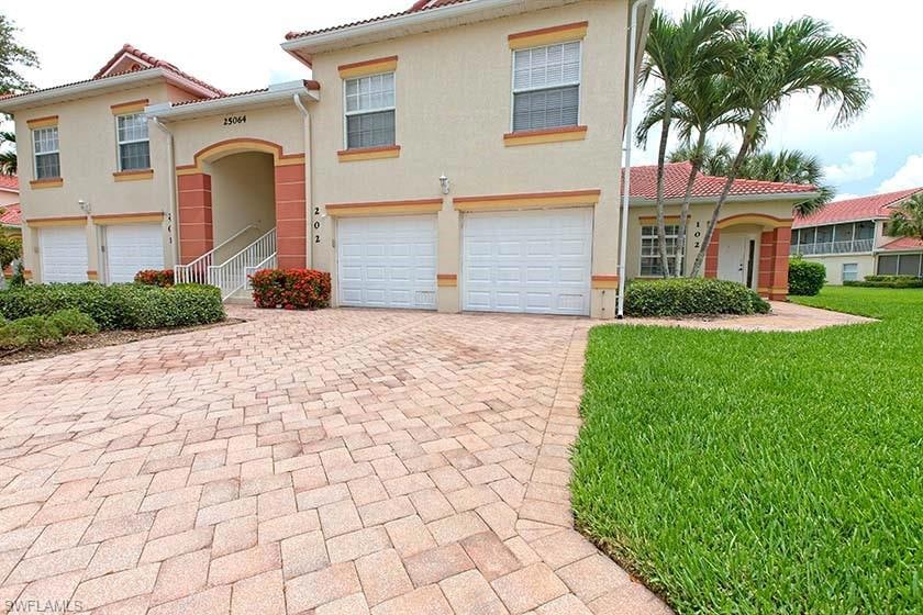 View of front of home with a garage, stucco siding, decorative driveway, a tile roof, and a front lawn